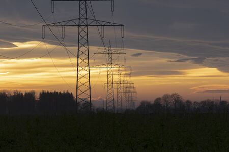 Electricity pylons power line at orange sunsetの写真素材