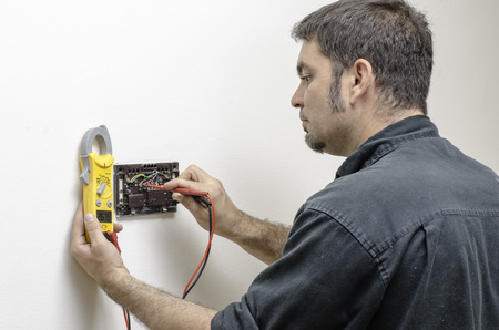 HVAC technician testing voltage on a mercury thermostat の写真素材