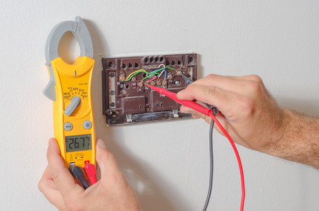 Technician testing thermstat voltage with a multi-meter