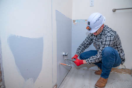 Plumber installing a water shut off valve in a bathroom that is being remodeledの写真素材