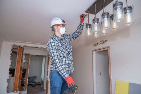 Electrician testing electrical current on a lighting fixture during a home remodel.