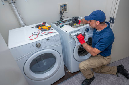 Appliance technician working under a kitchen sink installing a dishwasherの写真素材