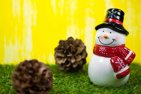 Christmas Decoration - Snow Man on Yellow Background with Selective Focus on Green Grassesの写真素材