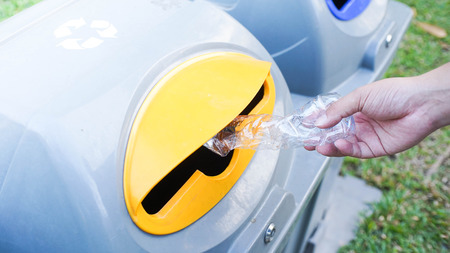 Hand throwing empty plastic bottle into the trashの写真素材