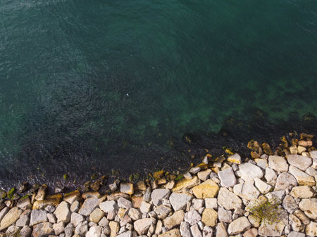 Large granite stones on the river bank. The edge of the river bank, water, road
