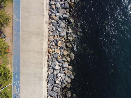 Large granite stones on the river bank. The edge of the river bank, water, road