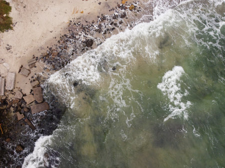 Beautiful sea waves crashing against the sandy beach with stines.の写真素材