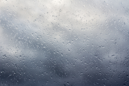 Stormy clouds through the wet windowの写真素材