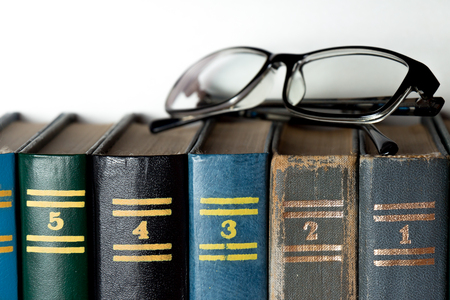 Glasses and different colorful Books on a white backgroundの写真素材