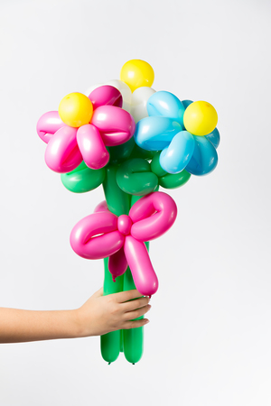 Child's hand holds a multicolored bouquet of air balloons close-upの写真素材