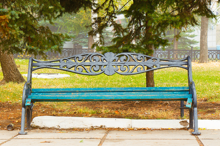 An empty bench is standing in the autumn park.の写真素材