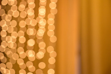 A lot of golden lights of a garland, background texture. Blurred bokeh lights in the room. Christmas lights of a garlandの写真素材