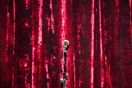 The microphone on the stand on the background of the red curtain of the scene.の写真素材