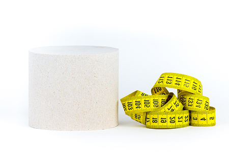 Measuring tape lying near a roll of toilet paper on a white backgroundの写真素材