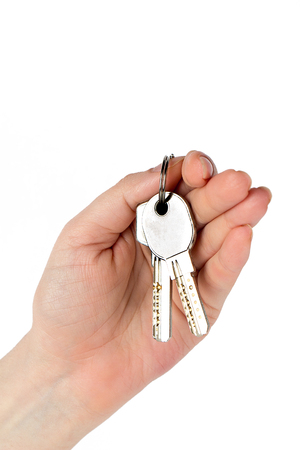 Female hand holds two keys isolated on white backgroundの写真素材