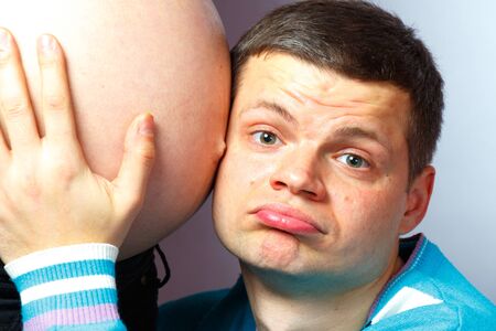 A man listens to the belly of a pregnant wifeの写真素材