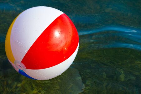 Beach ball floating in swimming pool abstract concept for summer vacations, relaxation and fun in...