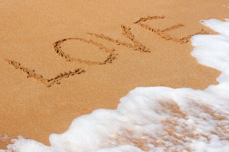 The inscription love on the sea sandy beachの写真素材