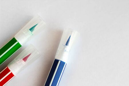 Red green blue felt-tip pens lie on a white sheetの写真素材