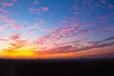 sunset in the cloudy sky above the industrial cityの写真素材