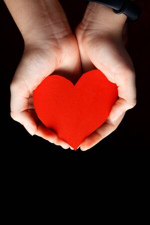 Red heart in the palms of a child.の写真素材
