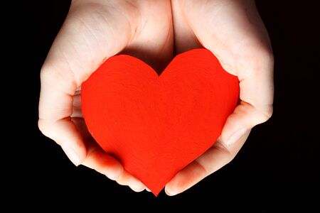 Red heart in the palms of a child.の写真素材
