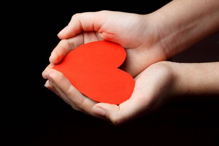 Red heart in the palms of a child.の写真素材