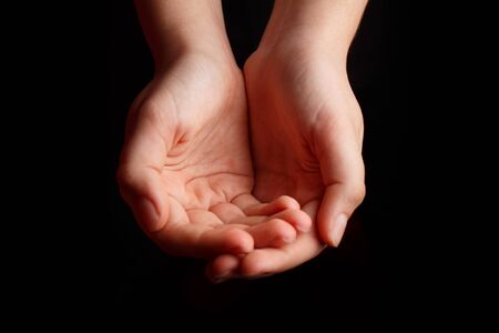 Childrens open palms are on a black background.の写真素材