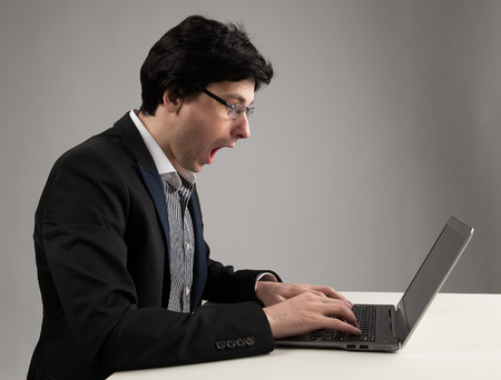 shocked business man staring at his laptop computerの写真素材
