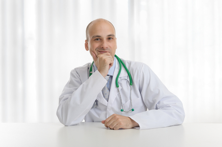 portrait of handsome male doctor sitting at a deskの写真素材