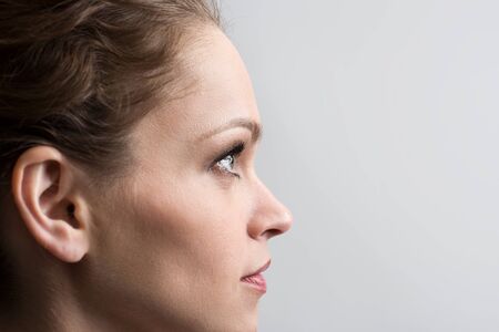 Beauty portrait of young girl in profile with brown hair. Isolated on gray backgroundの写真素材