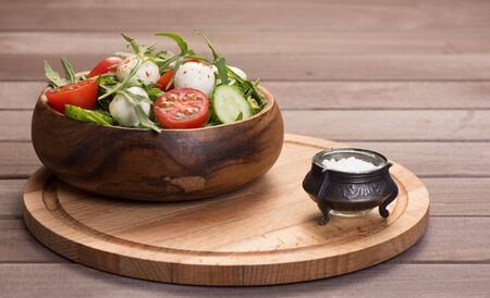 fresh vegetable salad with mozzarella and arugula on wooden backgroundの写真素材