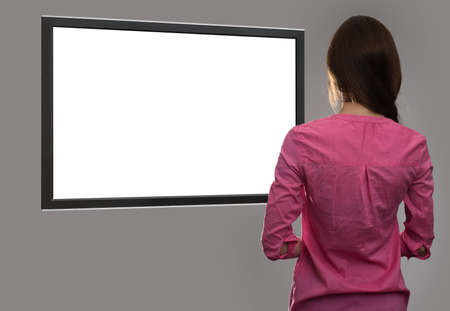 back view of young woman looking at blank tv screen with copy space