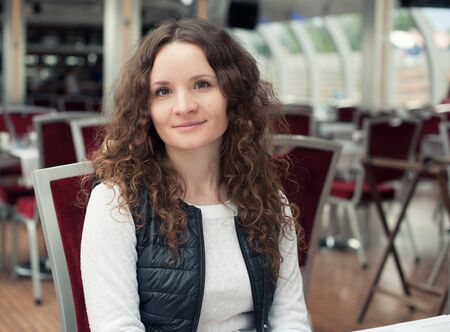pretty girl with curly hair sitting in cafeの写真素材