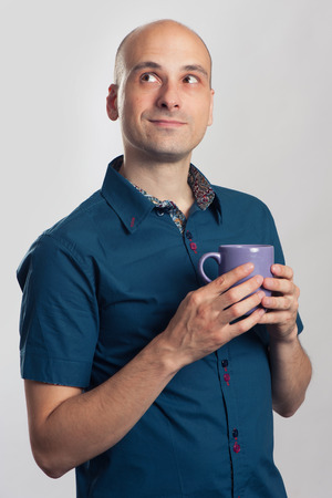 handsome bald man drinks a coffee or tea. Isolated on grayの写真素材