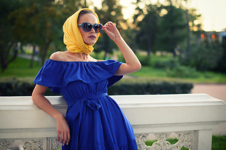 Fashionable Beautiful woman wearing blue dress, yellow headscarf and sunglasses. Outdoorの写真素材