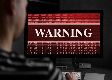 Man using laptop at night. Warning message on screen