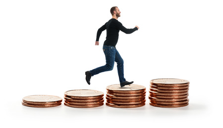 smiling man walking on Stack of coins isolated on white. Business Growth conceptの写真素材