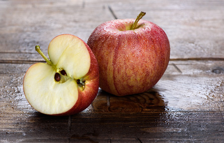 wet fresh red apple on rustic wooden table