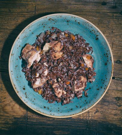 plate of brown rice with chicken on rustic wooden tableの写真素材