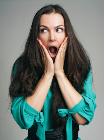 Surprised Woman looking at camera. Beautiful girl with long hair. Isolated on grey background. Expressive facial expressionsの写真素材