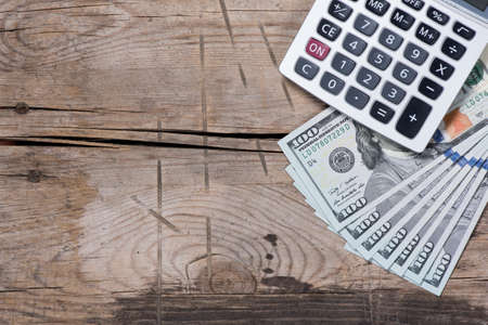 top view of a US dollars and calculator on old wooden tableの写真素材