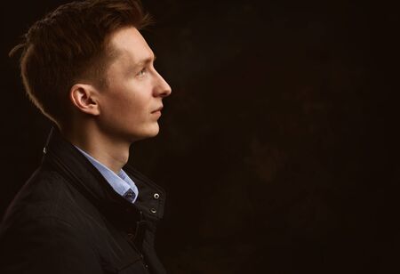 profile portrait of a handsome young man over black background