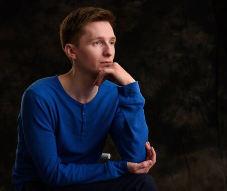 pensive thinking young man studio portrait over black backgroundの写真素材