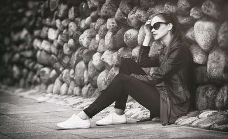 pretty sad girl sits on street. Outdoors portraitの写真素材