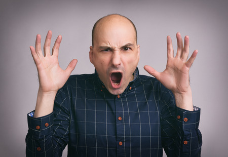 portrait of young bald angry man over gray backgroundの写真素材
