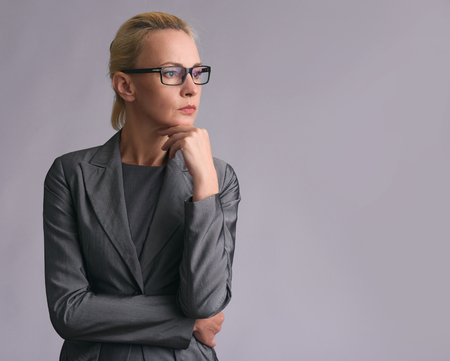 Beautiful business woman in glasses thinking isolated on grey backgroundの写真素材