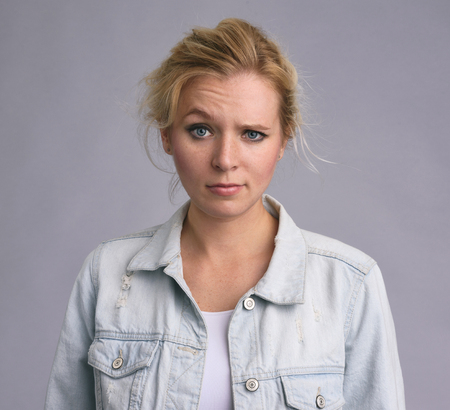 portrait of a serious beautiful woman raising an eyebrow. isolated on grey backgroundの写真素材