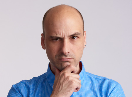 Serious bald man thinking. Angry guy isolated on greyの写真素材