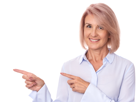 beautiful senior woman pointing finger to copy space. Isolated on whiteの写真素材